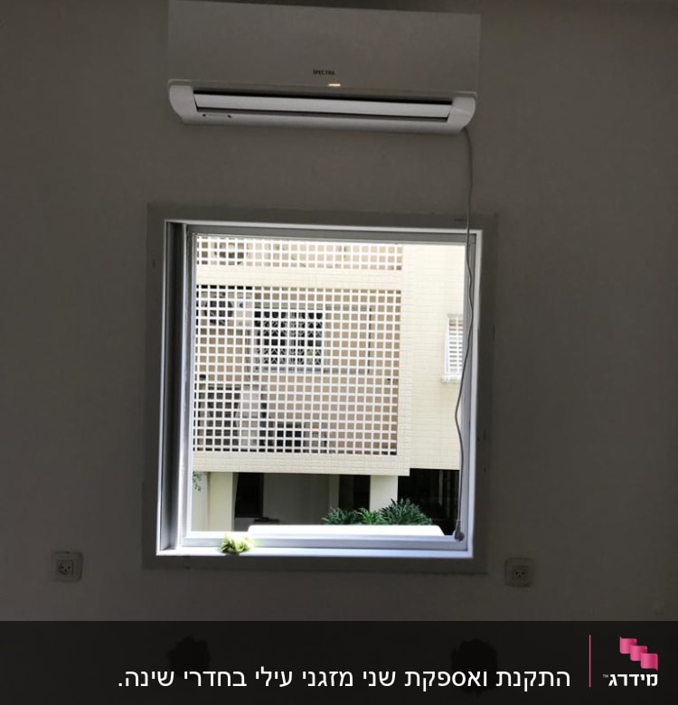מזגן מותקן מעל חלון עם כבל חשמל תלוי